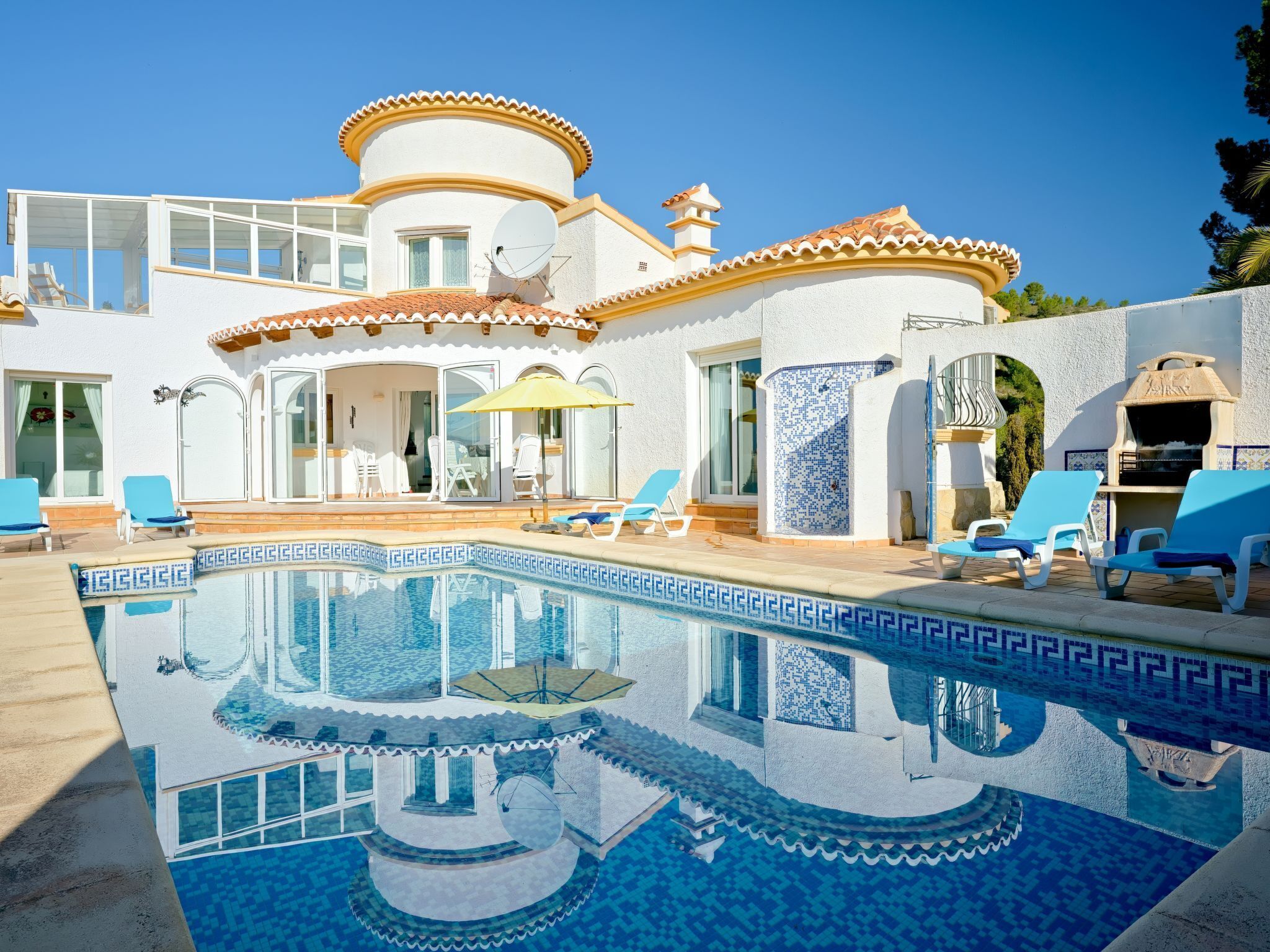 A modern villa with a swimming pool, outdoor seating, and a barbecue area.