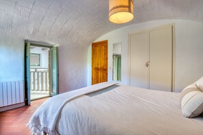 A bedroom with a bed, a wooden door, and a view of a balcony.