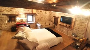 Una habitación acogedora con una cama, un sofá, un televisor y una chimenea.
