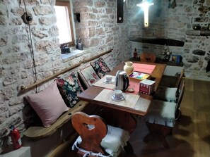 A rustic stone-walled room with a wooden table set for tea, featuring a kettle, cups, and a box of sugar. - Maison en Pierre (Fiastra)