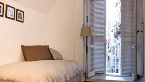 A bedroom with a bed, a floor lamp, and a window with blinds. - Holiday House Manuela Apartments 1 Piazza del Plebiscito (CENTRO)