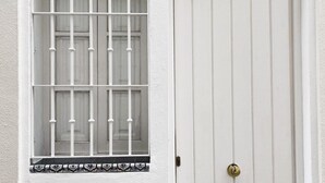 Eine weiße Tür mit Fenster, versehen mit Metallgitter und einer dekorativen Fliesenbordüre.