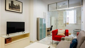 Ein modernes Wohnzimmer mit Fernseher, einem roten Sessel, einem grauen Sofa und einer Glasschrank.