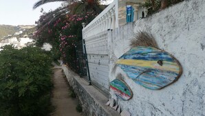 A pathway leading up a hill with a white wall on one side, decorated with colorful painted boards and a metal gate. - Camp Virpazar (Virpazar)