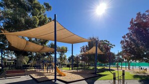A playground with shaded areas, a slide, and exercise equipment.