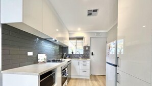 A modern kitchen with white cabinets, a black backsplash, and a built-in oven.