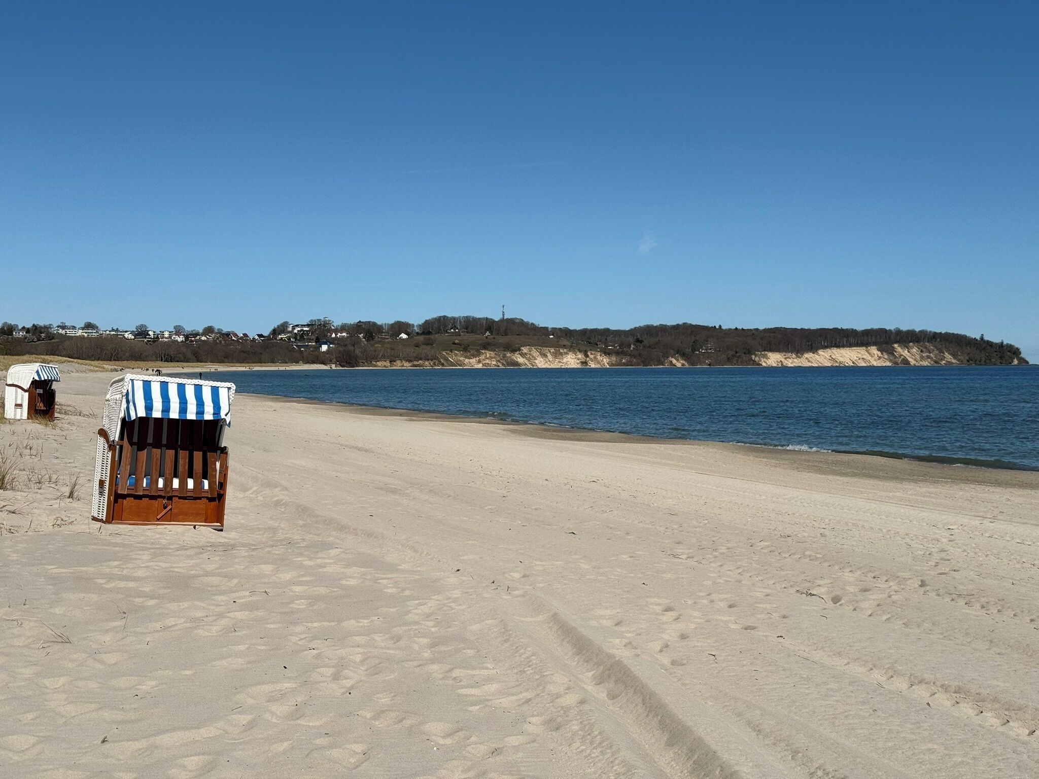 A beach with a single striped beach chair and a small structure, likely a beach hut, in the foreground.