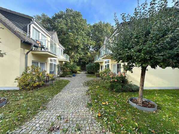 A courtyard with a cobblestone path leading to a building with a balcony.