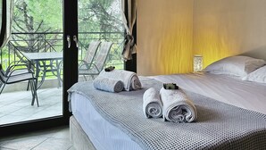 Un dormitorio con cama, vistas al exterior y una mesa con sillas afuera.
