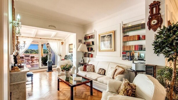 A spacious living room with a wooden floor, a white sofa, a coffee table, and a bookshelf filled with books. - Villa Elide with private pool (Massa Lubrense)