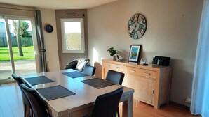 Un comedor con una mesa de madera, sillas negras y un reloj en la pared.