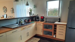 Una cocina moderna con un refrigerador de acero inoxidable, un horno empotrado, un lavamanos y un ventanal que proporciona luz natural.