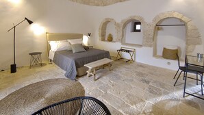 Un dormitorio acogedor con cama, mesitas de noche, una silla y paredes de piedra.