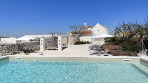 Un área de piscina con sillones reclinables y una pérgola.
