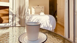 Una habitación con una cama, un tocador y una mesa de vidrio con un objeto blanco encima.