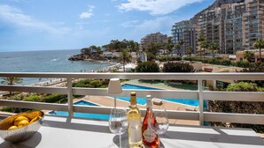 A balcony with a view of a beach, a pool, and a mountain. - Luxury Beachfront Apartment with Pool in Calpe for 4 Guests (Calpe)