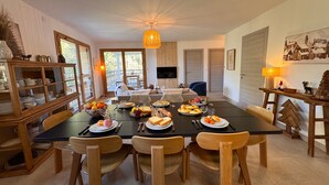 Een eetruimte met een tafel voor zes personen, omringd door houten stoelen. Een buffetkast met serviesgoed staat links.