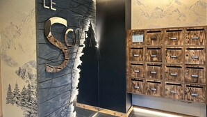 Een receptie met een groot 'LE SOLE' bord, een zwarte muur met een bergmuur en een houten lockersysteem.