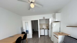 A compact living space with a dining area, kitchenette, and a grey sofa. - Sunny Duplex with Terrace, A/C, and Garage - Le Grau-du-Roi (Le Grau-du-Roi)