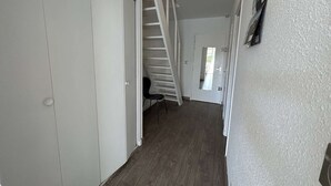 A narrow hallway with a wooden floor, a white door, and a white closet on the left. - Sunny Duplex with Terrace, A/C, and Garage - Le Grau-du-Roi (Le Grau-du-Roi)