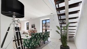 A modern interior with a dining area, a staircase, and a potted plant. - Queen of the Bay: Amazing Sea view in the heart of Carvoeiro (Carvoeiro)
