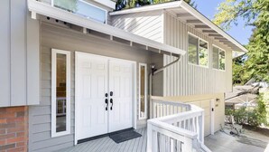 Ein zweigeschossiges Haus mit Veranda, Garage und überdachter Terrasse.