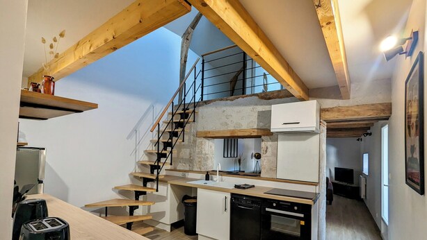 Une cuisine compacte avec un escalier en bois, des placards blancs et un four encastré.