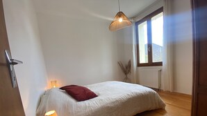 Una camera da letto con un letto, una lampada da comodino, un lampadario, una finestra con tende e un termosifone.