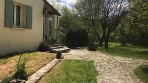 Un sentiero in pietra conduce a una casa con persiane verdi e un portico.