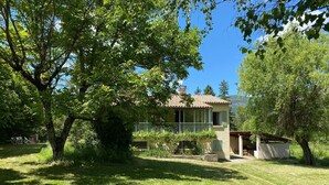 Una casa con un balcone, circondata da alberi e un prato curato.