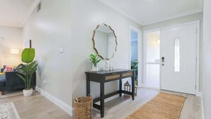A modern living room with a dark wooden console table, a mirror, and a potted plant.