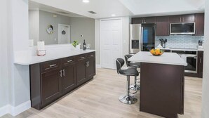 A modern kitchen with dark cabinets, a white countertop, and stainless steel appliances.