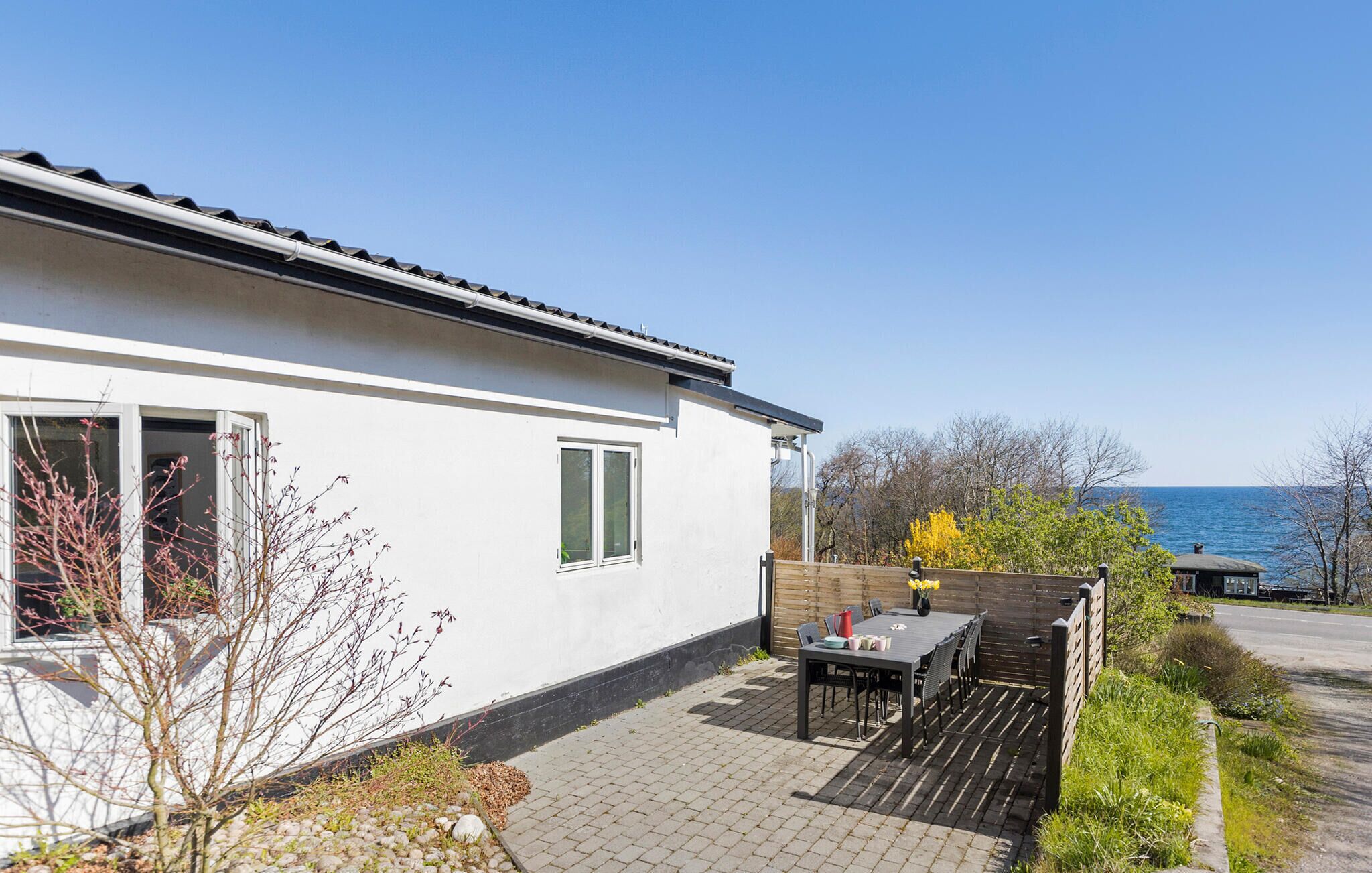 Et moderne hus med terrasse, et bord med stole og havudsigt.