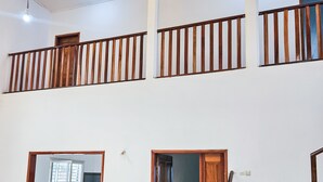 Un interior espacioso con un techo alto, una escalera de madera y varias puertas que dan a diferentes habitaciones.