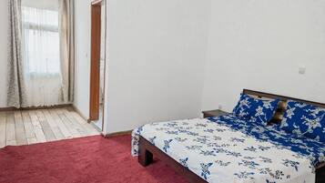 Ein Schlafzimmer mit einem hölzernen Bett, einem roten Teppich und einem Fenster mit Vorhängen.