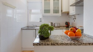 A modern kitchen with white cabinets, a granite countertop, a potted plant, and a fruit bowl. - Solemar @ Vale de Centeanes (Carvoeiro)