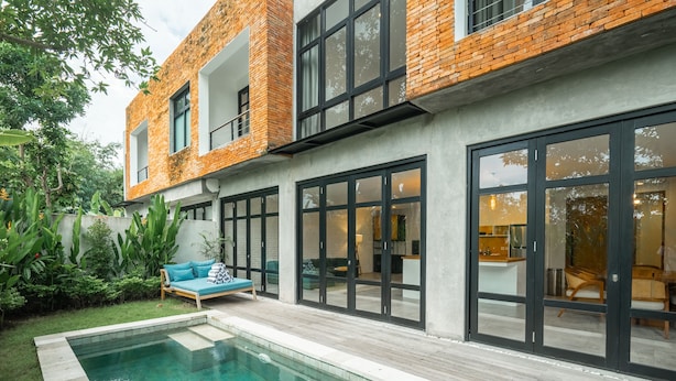 Ein modernes Haus mit Swimmingpool, großen Fenstern und einer Terrassenfläche.