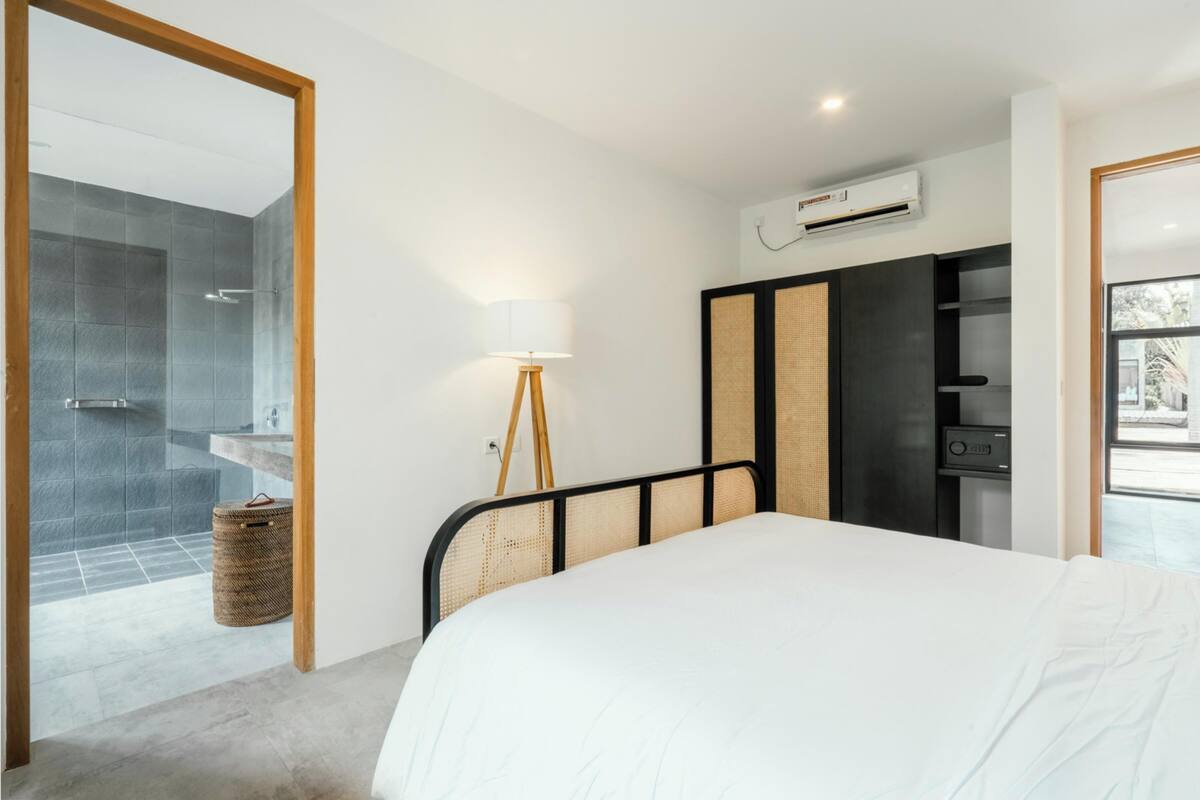 Ein modernes Hotelzimmer mit einem großen Bett, einer Nachttischlampe, einem Kleiderschrank und einem Duschbereich.