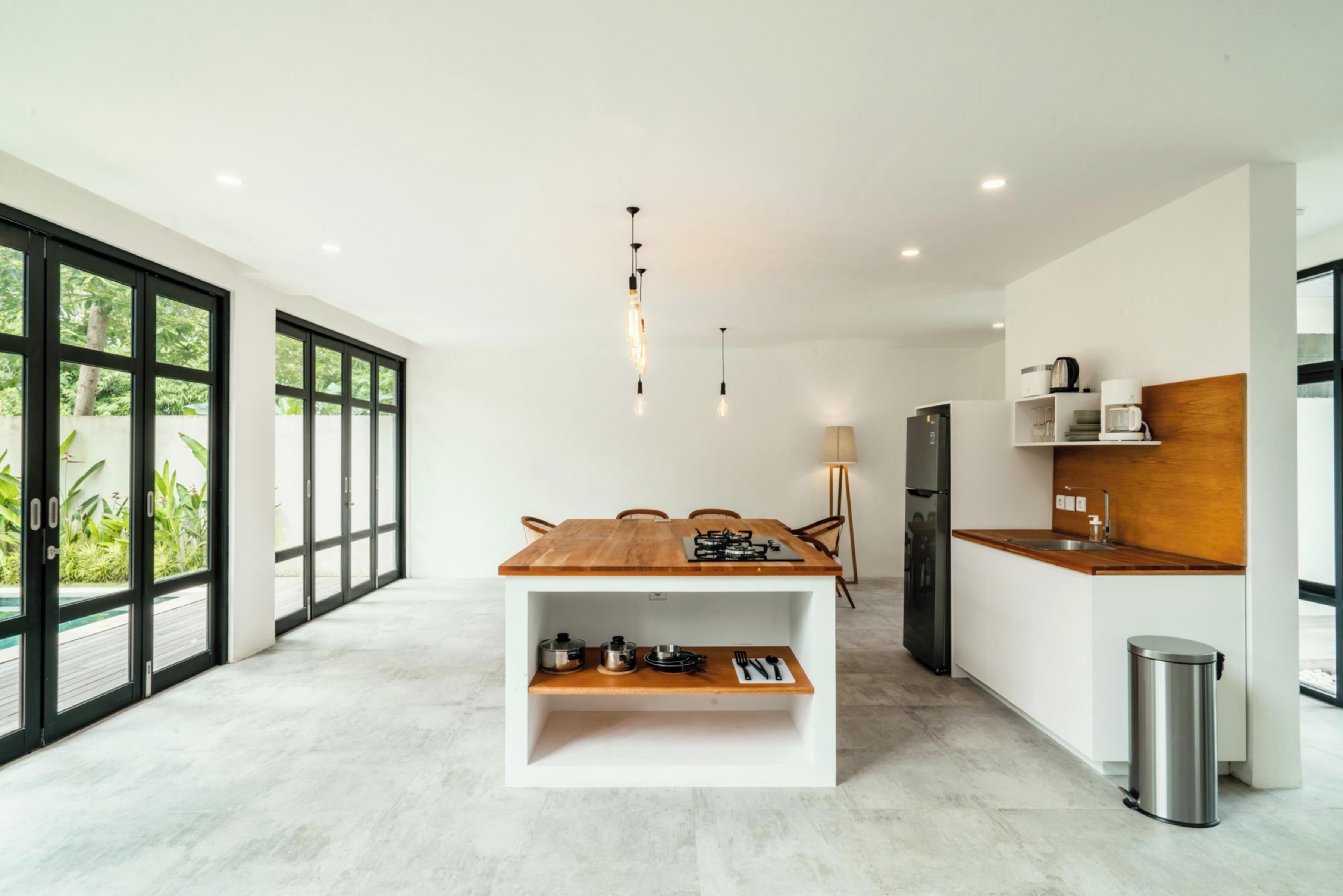 Una cocina moderna con una isla central, ventanas amplias y vistas al verdor.