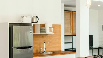 A modern kitchen with a stainless steel refrigerator, wooden countertop, and a hanging light fixture.