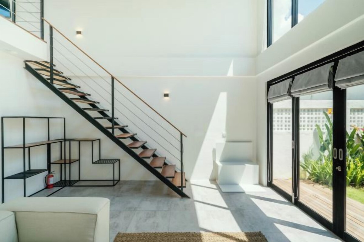 Ein modernes Interieur mit einer Treppe, einem weißen Sofa und einem großen Fenster.