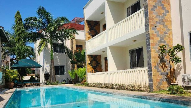 A two-story building with a swimming pool in front. - Lux Suites Diani Airstrip Villas  (Diani Beach)