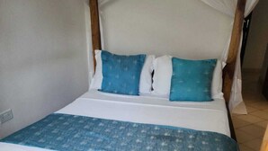 A bed with a wooden frame, white bedding, and blue pillows. - Lux Suites Diani Airstrip Villas  (Diani Beach)