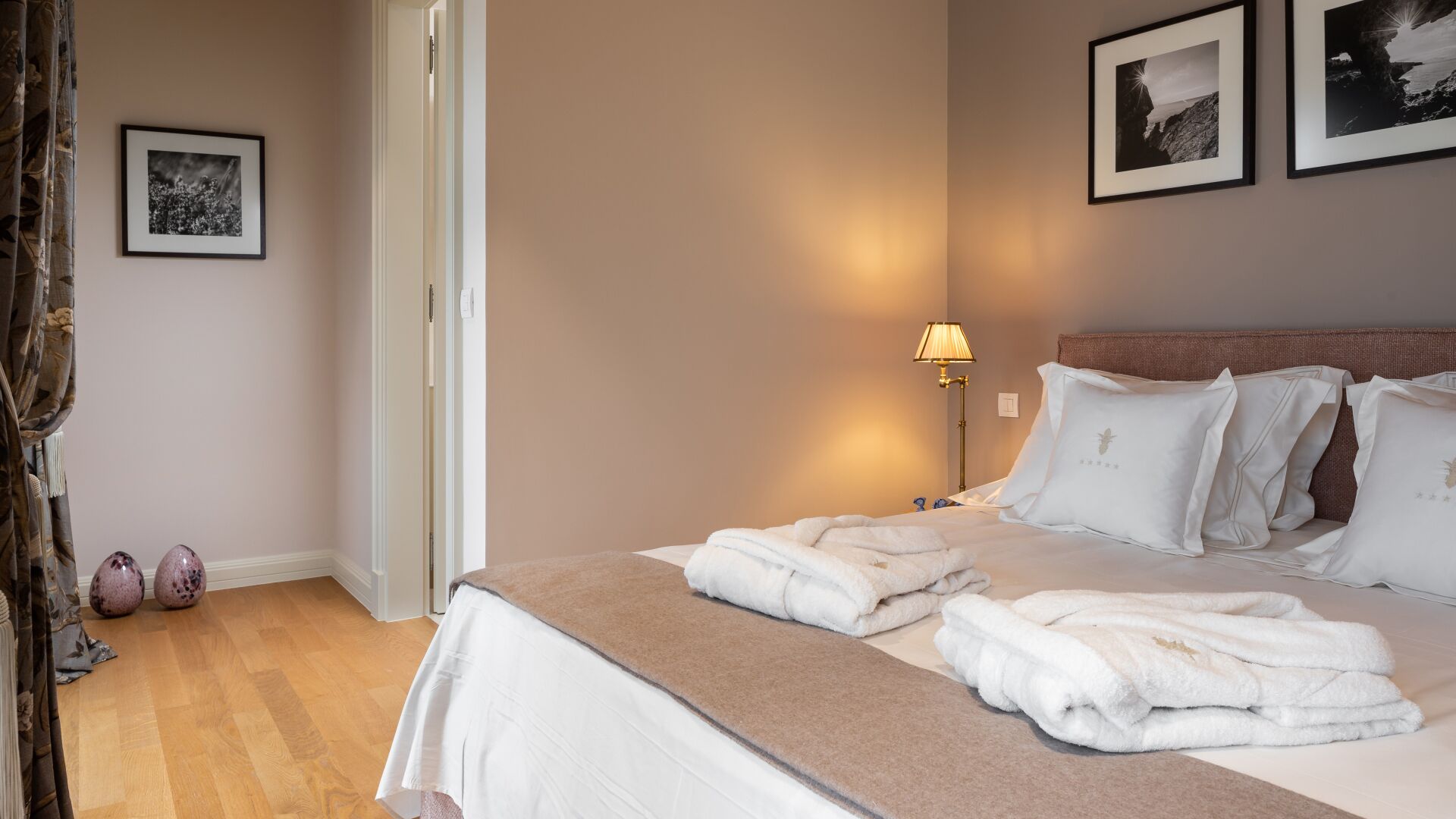 A hotel room with a bed, a bedside lamp, and two framed pictures on the wall.