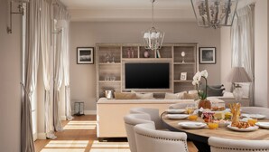 A modern dining area with a round table, chairs, a television, and a decorative shelf.