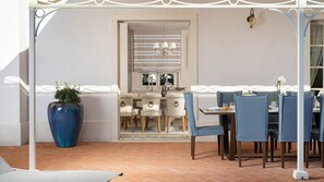 A dining area with a table and chairs, a large blue vase, and a view into a kitchen.