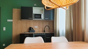 A compact kitchen with a microwave, sink, and a dining area with a table. - ARRIVEL Apartments Moosfeld (Munich)