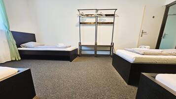 Une chambre d’hôtel avec deux lits simples, un banc en bois et un porte-manteau.