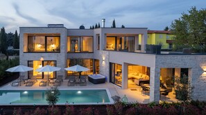 Een modern huis met twee verdiepingen, een zwembad, terras en een jacuzzi.