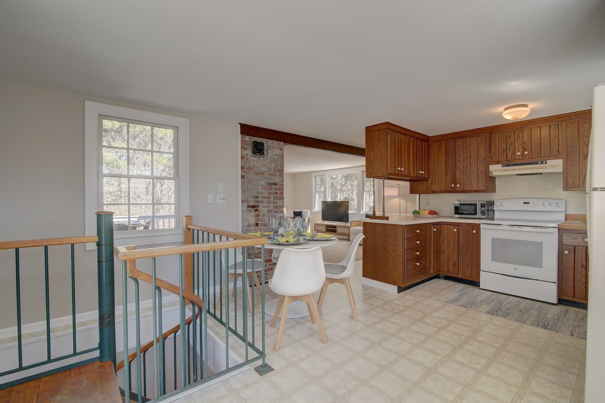 A kitchen with wooden cabinets, a white stove, and a dining area with a table and chairs.